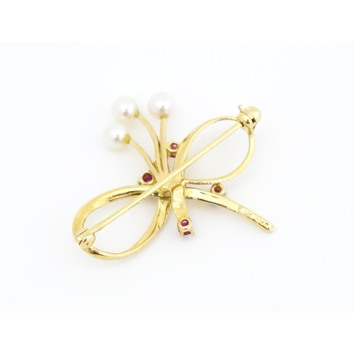 631 - A 10k gold brooch of bow form with pearl and ruby detail. Approx. 1 1/4