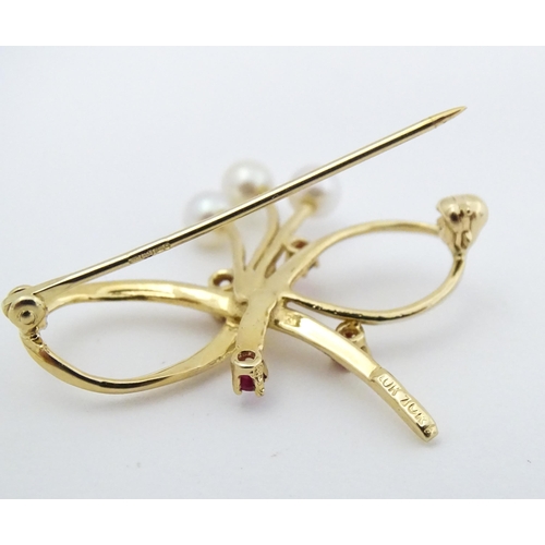 631 - A 10k gold brooch of bow form with pearl and ruby detail. Approx. 1 1/4