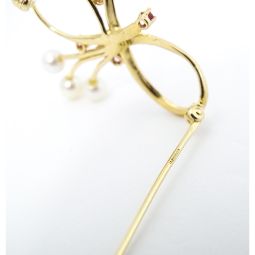 631 - A 10k gold brooch of bow form with pearl and ruby detail. Approx. 1 1/4