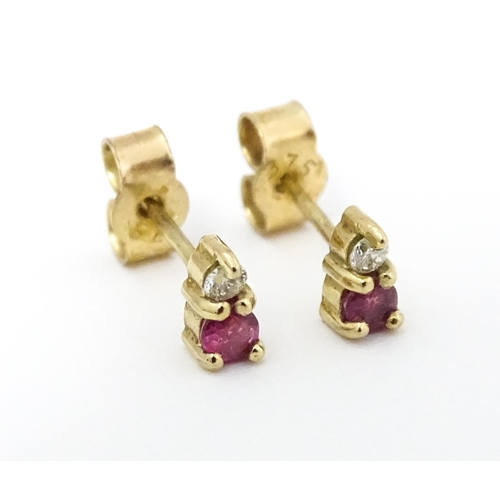 703 - A pair of 9ct gold stud earrings each set with a diamond and ruby. Approx 1/4