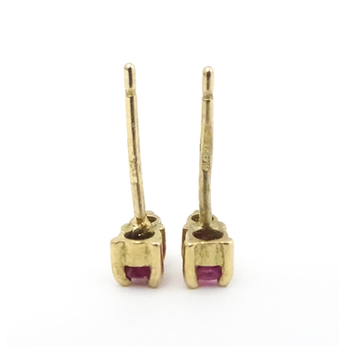 703 - A pair of 9ct gold stud earrings each set with a diamond and ruby. Approx 1/4