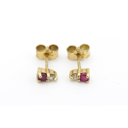 703 - A pair of 9ct gold stud earrings each set with a diamond and ruby. Approx 1/4