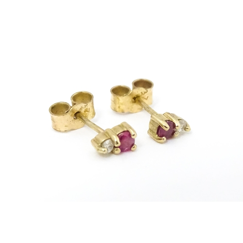 703 - A pair of 9ct gold stud earrings each set with a diamond and ruby. Approx 1/4