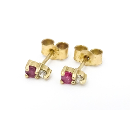 703 - A pair of 9ct gold stud earrings each set with a diamond and ruby. Approx 1/4