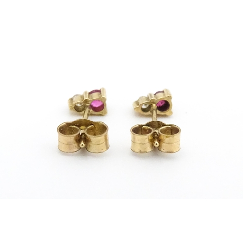 703 - A pair of 9ct gold stud earrings each set with a diamond and ruby. Approx 1/4