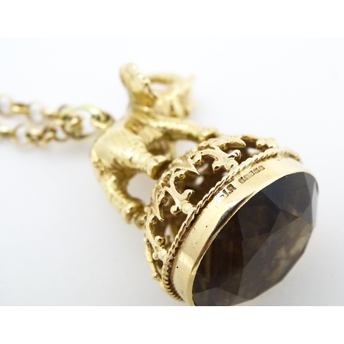 770 - A 9ct gold pendant fob seal surmounted by an elephant and set with facet cut smoky quartz under, on ... 