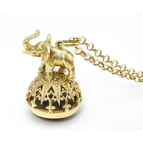 770 - A 9ct gold pendant fob seal surmounted by an elephant and set with facet cut smoky quartz under, on ... 