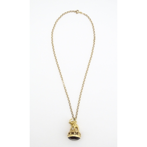 770 - A 9ct gold pendant fob seal surmounted by an elephant and set with facet cut smoky quartz under, on ... 