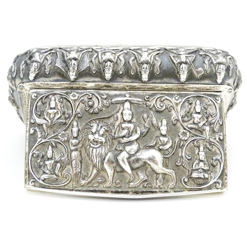 522 - A white metal snuff box decorated with various deities, including one to centre depicting a deity ri... 