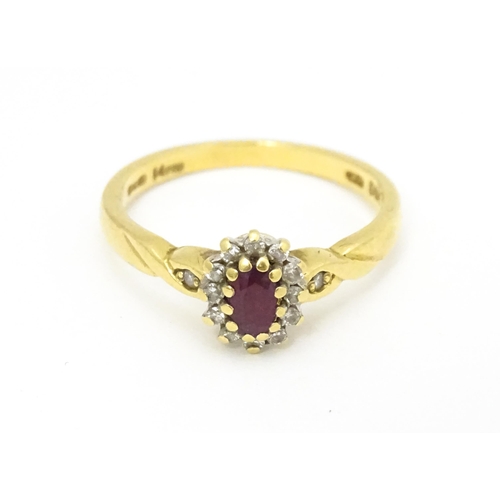 568 - An 18ct gold ring set with central ruby bordered by diamonds. Ring size approx. M 1/2.