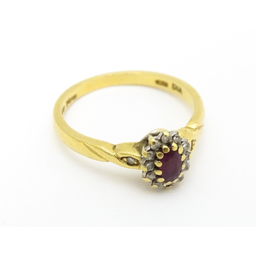 568 - An 18ct gold ring set with central ruby bordered by diamonds. Ring size approx. M 1/2.