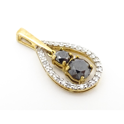 628 - A 9ct gold pendant set with banded diamonds and central dark coloured stones. Approx. 7/8