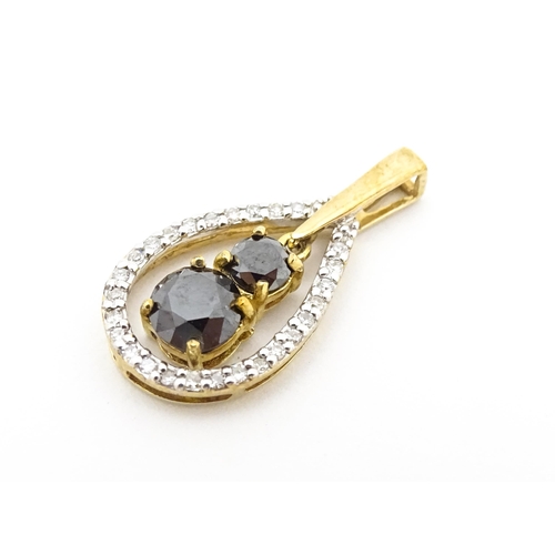 628 - A 9ct gold pendant set with banded diamonds and central dark coloured stones. Approx. 7/8