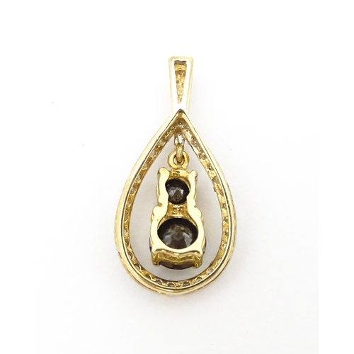 628 - A 9ct gold pendant set with banded diamonds and central dark coloured stones. Approx. 7/8