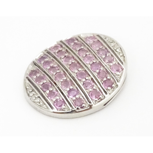 638 - A 9ct white gold pendant of oval form set with diamonds and pink sapphires. Approx. 7/8