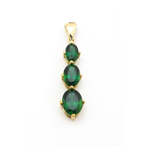 670 - A 9ct gold pendant set with three graduated green stones. Approx. 1 1/42 long