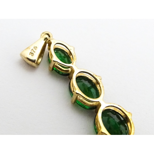 670 - A 9ct gold pendant set with three graduated green stones. Approx. 1 1/42 long