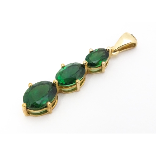 670 - A 9ct gold pendant set with three graduated green stones. Approx. 1 1/42 long