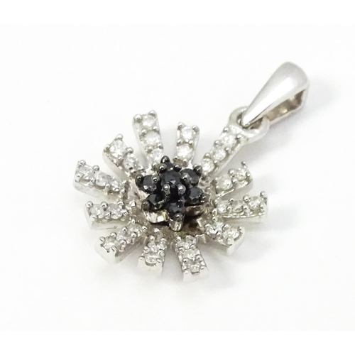 696 - A 9ct white gold pendant of daisy form set with black and white diamonds. Approx. 3/4