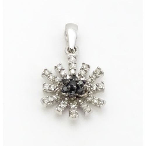 696 - A 9ct white gold pendant of daisy form set with black and white diamonds. Approx. 3/4