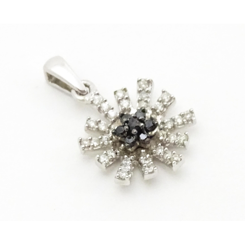 696 - A 9ct white gold pendant of daisy form set with black and white diamonds. Approx. 3/4