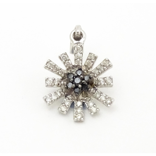 696 - A 9ct white gold pendant of daisy form set with black and white diamonds. Approx. 3/4