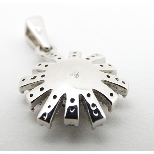 696 - A 9ct white gold pendant of daisy form set with black and white diamonds. Approx. 3/4