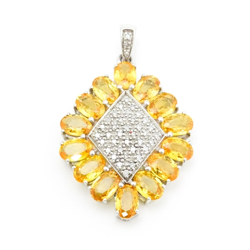 698 - A 9ct white gold pendant set with diamonds and yellow stones. Approx. 1 1/2