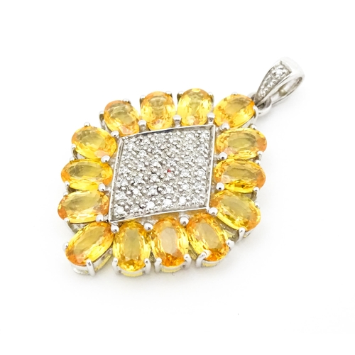 698 - A 9ct white gold pendant set with diamonds and yellow stones. Approx. 1 1/2