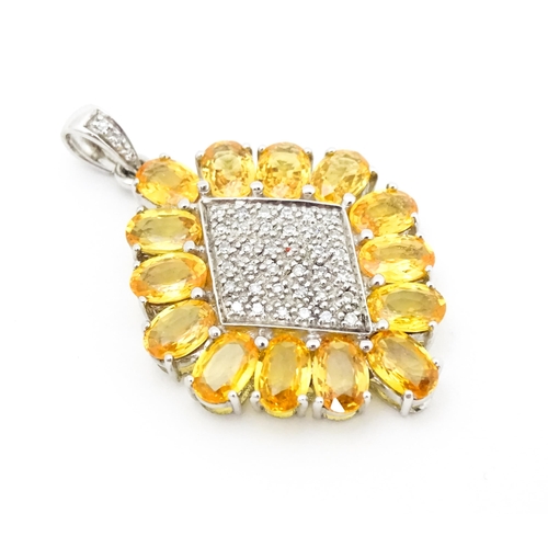 698 - A 9ct white gold pendant set with diamonds and yellow stones. Approx. 1 1/2