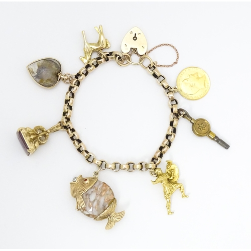 768 - A 9ct gold charm bracelet set with various gold and gilt metal charms to include a half sovereign, f... 