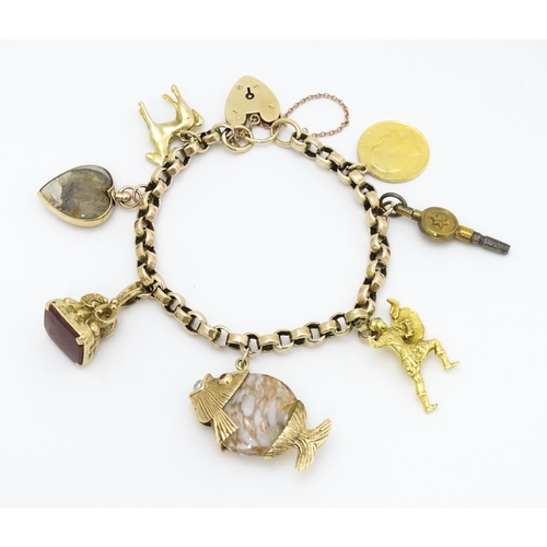 768 - A 9ct gold charm bracelet set with various gold and gilt metal charms to include a half sovereign, f... 