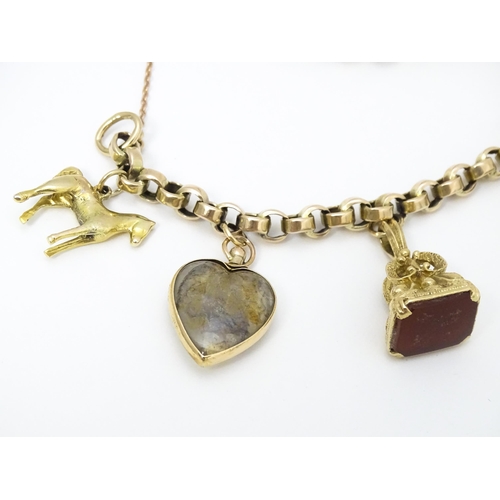 768 - A 9ct gold charm bracelet set with various gold and gilt metal charms to include a half sovereign, f... 