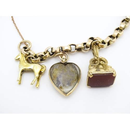 768 - A 9ct gold charm bracelet set with various gold and gilt metal charms to include a half sovereign, f... 