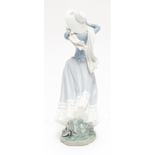 103 - A Lladro figure Spring Breeze, no. 4936, modelled as a lady with a hat. Marked under. Approx. 14 1/4... 