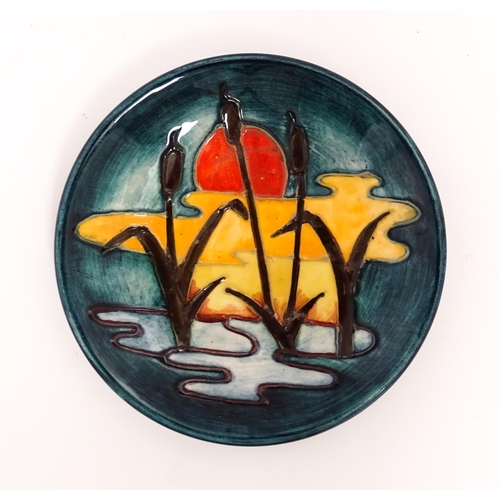 142 - A small Moorcroft plate decorated in the Reeds at Sunset pattern. Marked under. Approx. 4 3/4