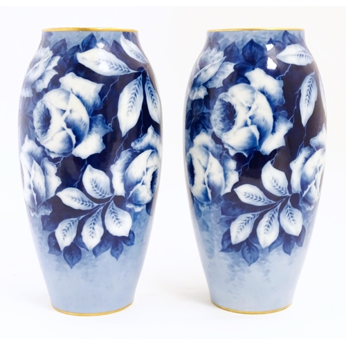 155 - A pair of large French porcelain vases, the blue ground decorated with roses and foliage. With bande... 