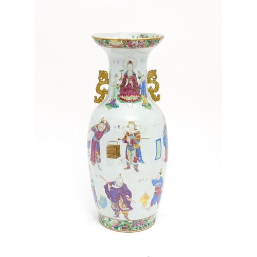 A large Chinese famille rose vase with twin handles, decorated with theatrical Wu Shuang Pu figures, vases, censers, scrolls, foo dogs, birds, Character script, etc. With floral and foliate borders and detail to inner rim. Approx. 23 3/4" high