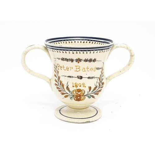 69 - A 19thC twin handled loving cup with hand painted decoration titled Peter Bates 1802 with floral and... 