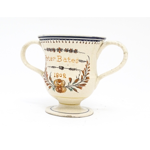 69 - A 19thC twin handled loving cup with hand painted decoration titled Peter Bates 1802 with floral and... 