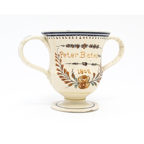 69 - A 19thC twin handled loving cup with hand painted decoration titled Peter Bates 1802 with floral and... 