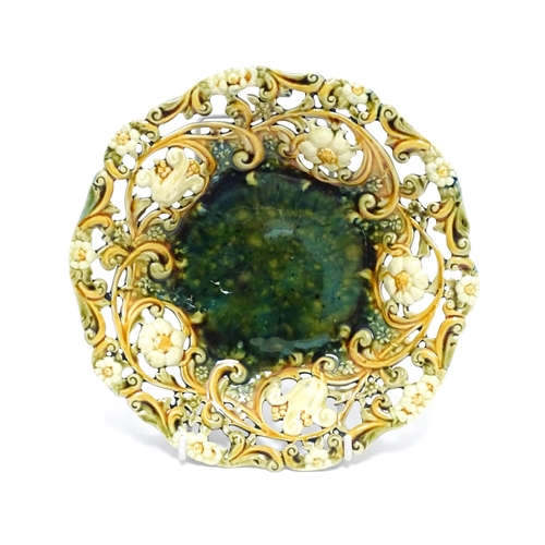 75 - A Linthorpe majolica plate with mottled green glaze to centre bordered by floral and pierced decorat... 