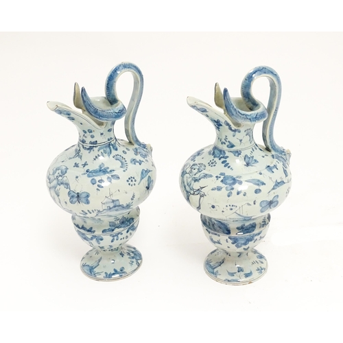 81 - A pair of Italian Cantagalli blue and white ewers decorated with cupids, flowers, foliage, butterfli... 