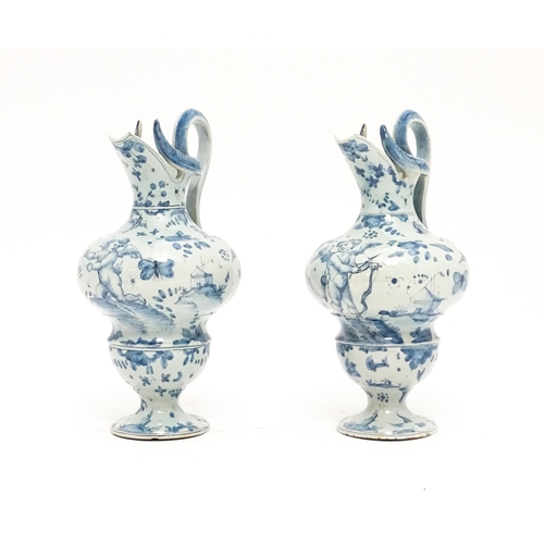 81 - A pair of Italian Cantagalli blue and white ewers decorated with cupids, flowers, foliage, butterfli... 