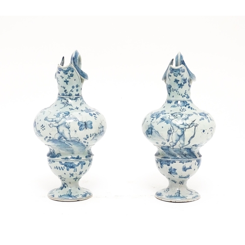 81 - A pair of Italian Cantagalli blue and white ewers decorated with cupids, flowers, foliage, butterfli... 