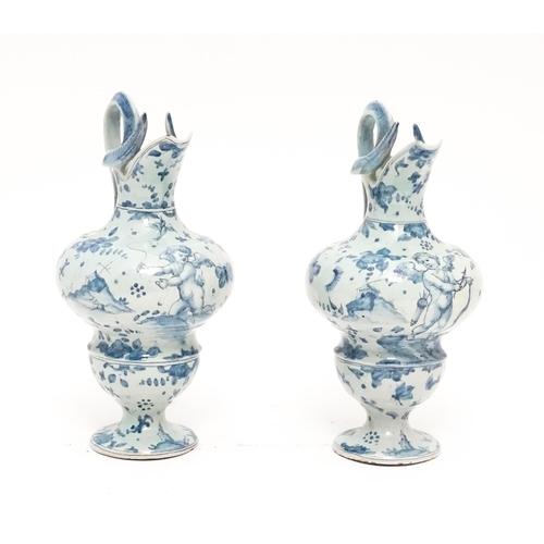 81 - A pair of Italian Cantagalli blue and white ewers decorated with cupids, flowers, foliage, butterfli... 