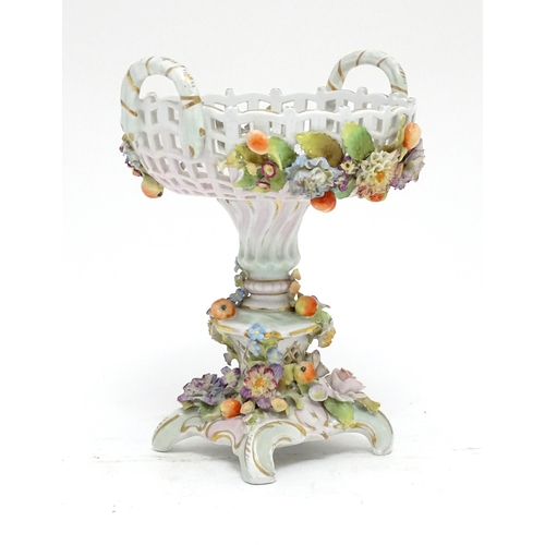 90 - A German centrepiece / comport of pedestal form, the basket formed bowl with twin handles, pierced d... 