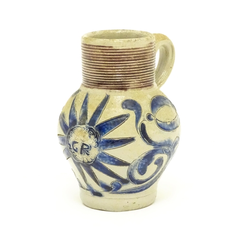 97 - A German Westerwald stoneware jug with single handle, the body with blue painted detail and initials... 