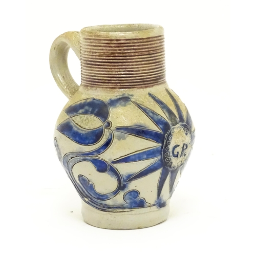 97 - A German Westerwald stoneware jug with single handle, the body with blue painted detail and initials... 