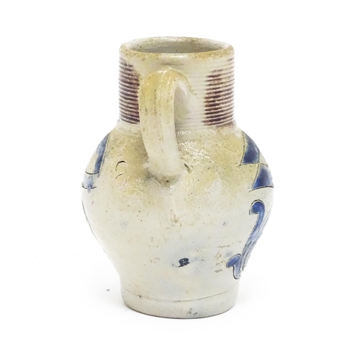 97 - A German Westerwald stoneware jug with single handle, the body with blue painted detail and initials... 